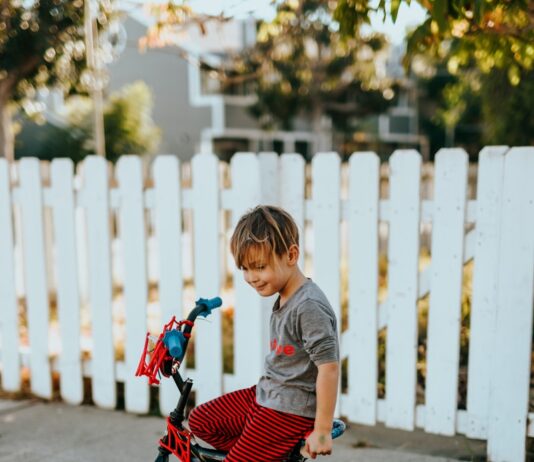 ‘찾아가는 어린이 자전거 교통 안전교육’ 실시 girl in red and black bicycle suit standing beside white wooden fence during daytime