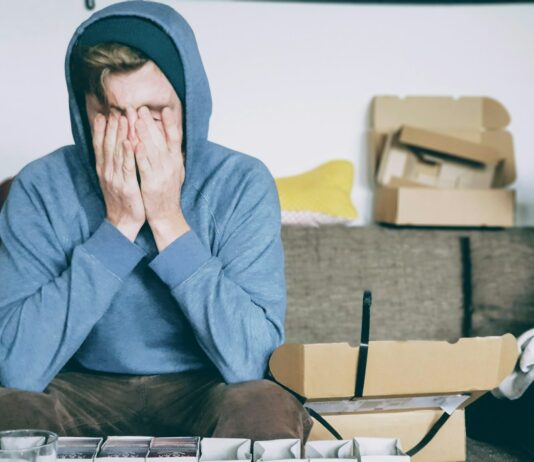 직장 내 건강을 위한 스트레스 관리의 필요성 man covering face with both hands while sitting on bench